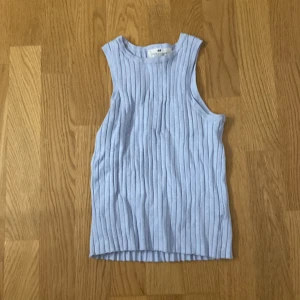 Ljusblå ribbad linnetopp från H&M - Säljer en ljusblå ribbad linnetopp från H&M. Toppen är ärmlös och har en stilren design som passar perfekt för varmare dagar. Den är tillverkad i ett mjukt och bekvämt material.