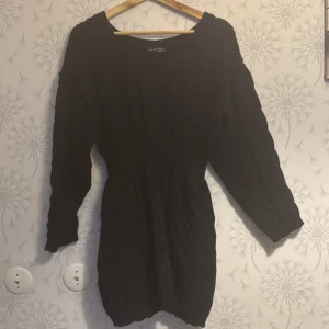 Svart stickad klänning - Säljer en svart stickad klänning med långärmad design. Klänningen har en åtsittande passform och är perfekt för kyligare dagar. Den har en enkel och stilren look som passar till många tillfällen.