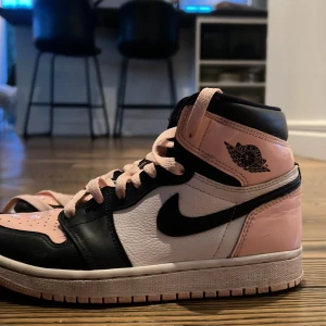 Nike Air Jordans i rosa och svart - Snygga Nike Air Jordans i en cool kombination av rosa, svart och vitt. Skorna har klassisk snörning och den ikoniska Air Jordan-loggan på sidan. Perfekta för dig som vill ha en stilren och sportig look.