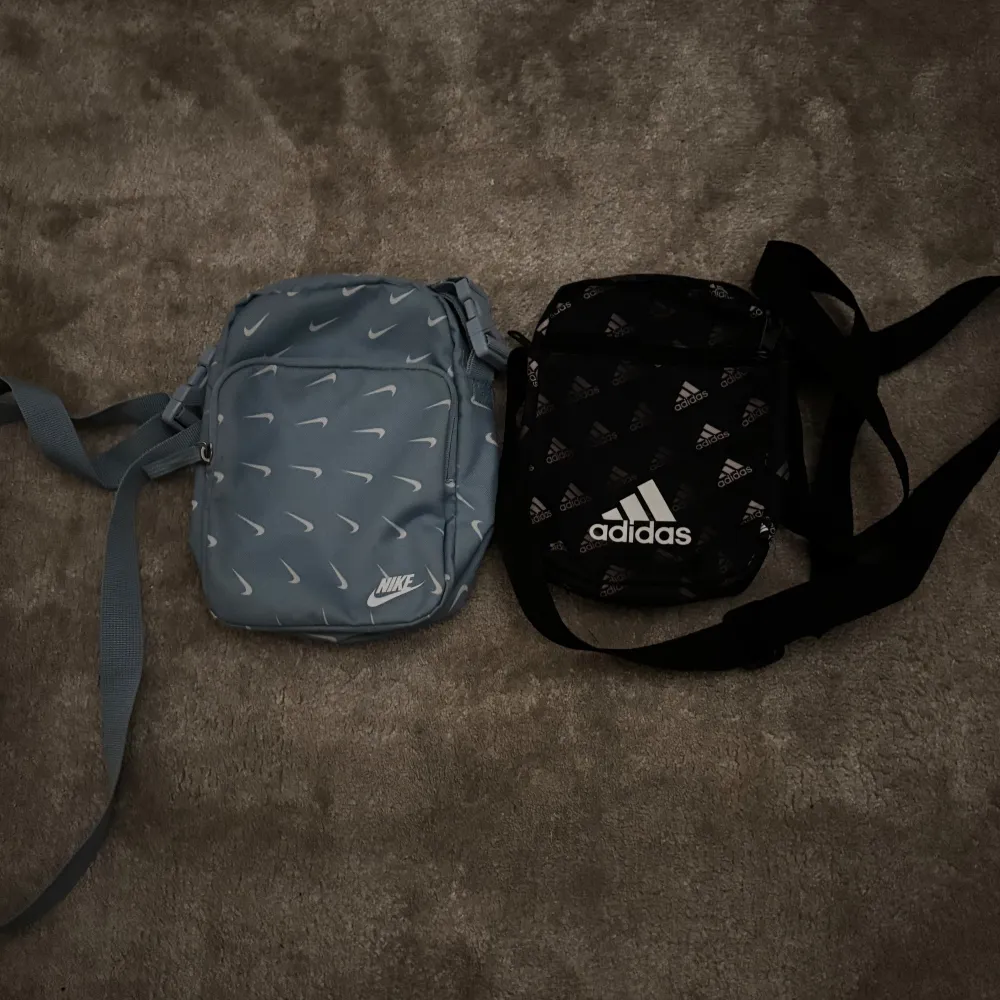 Två stilrena axelväskor, en från Nike i ljusblått med vita loggor och en från Adidas i svart med vita loggor. Perfekta för att bära med sig det nödvändigaste på språng. Justerbara axelremmar för bekväm passform. Kontakta gärna vid minsta fråga! Säljer även väskorna styckvis kontakta för mer info.. Laukut & Käsilaukut.