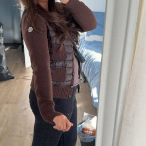 Cardigan jacka, Moncler - Snygg brun quiltad jacka från Moncler med stickade ärmar och ribbad kant. Jackan har knappar framtill och två praktiska fickor. Perfekt för kyligare dagar med sin stilrena design och varma material. Passar xs/s