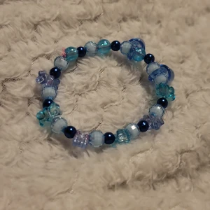 Blått pärlarmband - Charmigt armband med blå och turkosa pärlor i olika nyanser och former. Perfekt för att lägga till en färgglad touch till din outfit. Elastiskt band för enkel passform.