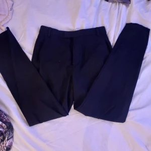 Svarta kostymbyxor från Lindex - Snygga svarta kostymbyxor från Lindex i modellen Polly. De har en klassisk design med raka ben och hällor för bälte. Perfekta för en stilren look.