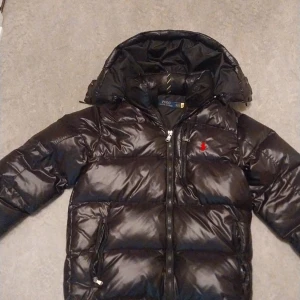 Svart dunjacka från Polo Ralph Lauren - Säljer en ralph lauren jacket eftersom att den är för liten. Jackan har en liten skrapa vid luvan som ni se på bilden, men är i bra skick 