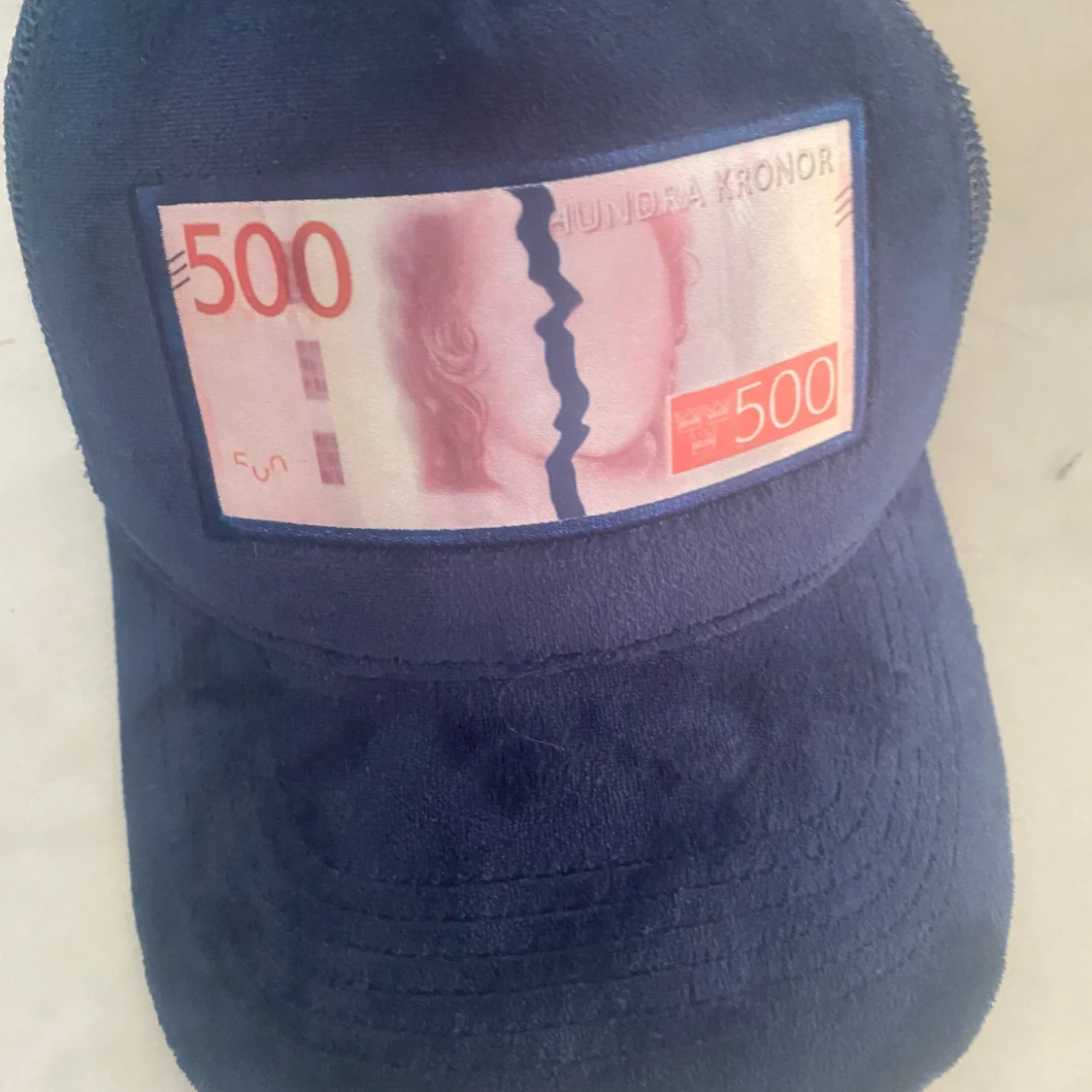 Blå keps med 500-kronorsmotiv