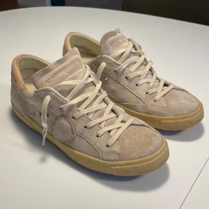 Beige sneakers i mocka - Snygga beige sneakers från Philippe Model i mjuk mocka med snörning. 9/10 nästan i ny skick. Tveka inte med att höra av dig om du har några frågor eller bud.