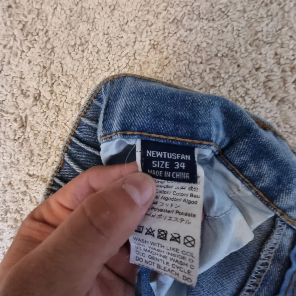 Säljer ett par klassiska blå jeans från Newtusfan i storlek 34. De har en straight passform och är tillverkade i bomull och polyester. Perfekta för vardagsbruk med en bekväm midja och traditionella fem fickor. Den är lite baggy. Jeans & Byxor.