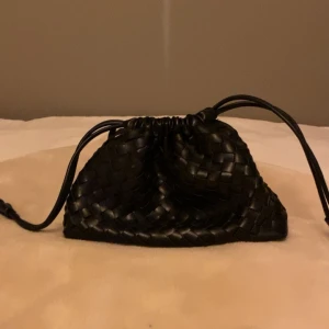 Flätad väska - Säljer denna svarta flätade väska ifrån hunkemöller. Väskan är använd men i gott skick! Väskan har inga defekter.  Hör av er om frågor🙌
