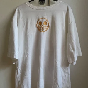 Vit t-shirt med anime-tryck - Säljer en vit t-shirt med ett coolt anime-tryck på framsidan. T-shirten har en avslappnad passform och är gjord i mjuk bomull. T-shirt är oversized ock knappt använt. Kontakta för mer information 
