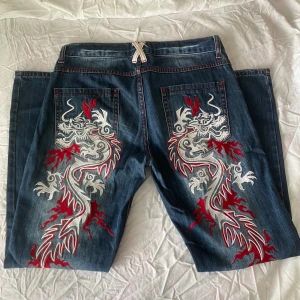 Vintage baggy jeans Y2k print  - Supercoola vintage baggy jeans med volt snyggt print  lite vita fläcken på benet, har även sytt in skosnören för att knyta byxorna men de kan lätt tas ut  Står att det är storlek 34 men de är ganska stora så skulle nog säga M eller L