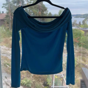 Blå långärmad topp från Gina Tricot - Säljer en snygg blå långärmad topp från Gina Tricot. Den har en unik off-shoulder design som ger en stilren look. Perfekt för både vardag och fest!