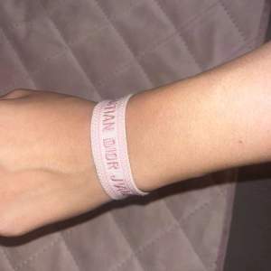 Säljer ett supersnyggt rosa armband från Dior. Det är vävt med texten 'Christian Dior J'Adior' och har söta tofsar i ändarna. Perfekt armband för att ge din outfit en lyxig touch. För övrig information skriv till mig privat. Mvh// Trendsettar