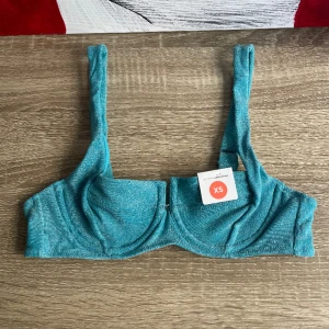 Glittrig blå topp  - Glittrig blå topp i storlek XS. Egentligen är det en bikintopp men kan även has som festtopp till exempel under en kavaj. Originalpris 229kr. Men jag säljer för 30kr🩵
