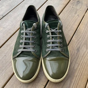 Gröna sneakers med mocka och lackdetaljer - Säljer ett par snygga gröna sneakers med en cool kombination av mocka och lackdetaljer. Skorna har en djup grön färg med snörning i matchande ton. Sulan är i en ljusare beige nyans som ger en fin kontrast. Perfekta för både vardag och fest!