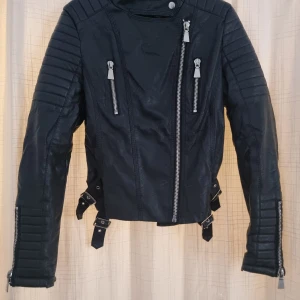 Chiquelle skinnjacka i strl 40 - Snygg skinnjacka från Chiquelle i storlek 40. Är lite nött i ryggen högst upp samt inuti jackan vid lappen vilket kan ses på bilderna, annars jättefin jacka. Perfekt för höst och vår!