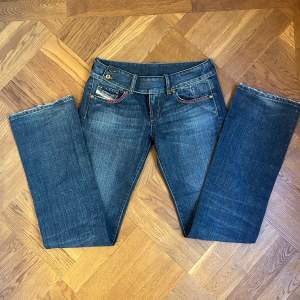 Säljer ett par snygga blå jeans från Diesel. De har en bootcut-stil och är lågmidjada. Jeansen har coola detaljer som kontrastsömmar och en liten ficka med Diesel-logga. Köpta secondhand i Köpenhamn! Innerbenslängd: 87 cm