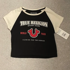 Svart och vit croppad t-shirt från True Religion - Säljer en cool svart och vit croppad t-shirt från True Religion. Perfekt för en avslappnad stil!Priset kan diskuteras😊