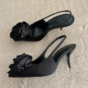 Svarta klackar med blomma - Svarta klackar med en blomma framtill från NAKD. Helt oanvända. 