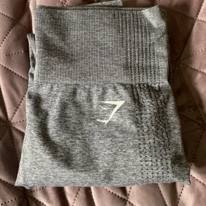 Gymshark tights - Ett par grå gymshark tights i nyskick. Hittar inte storlek tyvärr men skulle gissa på M! Kommer inte till användning 😌