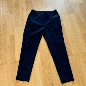 Svarta byxor - Säljer ett par marinblå byxor i bra skick. De har en enkel och stilren design med elastisk midja för extra komfort. Perfekta för både vardag och lite mer uppklädda tillfällen.