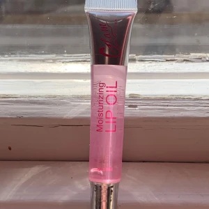 Fuktgivande läppolja - En superfin fuktgivande läppolja i en genomskinlig rosa nyans. Plasten är kvar och helt ny. Den kommer i en smidig tub med silverlock och har en glansig finish. Perfekt för att hålla läpparna mjuka och återfuktade hela dagen!