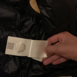 Svart pufferjacka från Moncler - Säljer en snygg svart pufferjacka från Moncler. Den är perfekt för kyliga dagar och har en stilren design med dragkedja framtill och två praktiska fickor. Jackan är i bra skick och redo för nya äventyr!