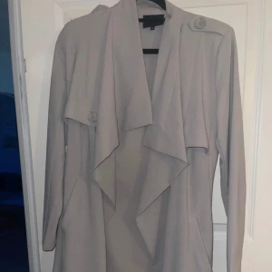Kappa från Vero Moda  - Jätte fin kappa, med band i midjan för att stänga.  Ljusgrå färg. Väldigt bra skick. 