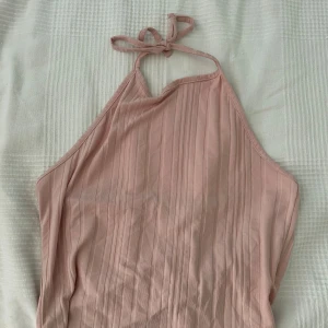 Rosa ribbad halterneck topp från Monki - Säljer en superfin rosa halterneck topp från Monki. Den är ribbad och har en snygg knytning i nacken. 