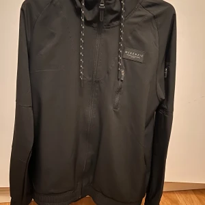 Svart jacka från McKenzie - Snygg svart jacka från McKenzie med dragkedja och huva. Säljer min knappt använda vindjacka från Mckenzie, den är i väldigt fint skick. Storlek Medium. Hör av dig vid frågor eller funderingar!