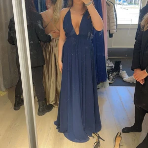 Mörkblå balklänning  - Mörkblå långklänning med v-ringning som jag sytt ihop lite på andra bilden använd endast en gång, köpt i en butik i Stockholm, ordinarie pris 3000
