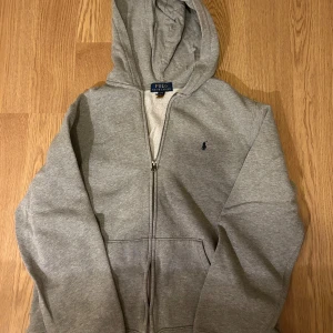 Grå hoodie från Ralph Lauren - Säljer en klassisk grå hoodie från Ralph Lauren. Storleken är XL i ungdom vilket motsvarar S i herr. Priset kan sänkas vid snabb affär.