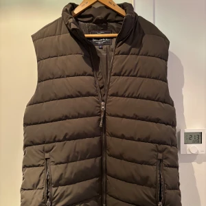 Grön dunväst från Bondelid - Säljer denna gröna dunväst från Bondelid i storlek S. Västen ser brun ut på bilderna men är mer åt det gröna hållet. Säljer p.g.a tröttnat på den. Västen är i princip i nyskick då den bara använts ett fåtal gånger. Pris kan diskuteras vid snabb affär.