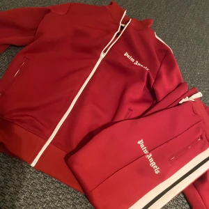 Röd hoodie från Palm Angels - Säljer en snygg röd hoodie från Palm Angels med vit dragkedja och logga på bröstet. Perfekt för en avslappnad stil. Hoodien har långa ärmar och en bekväm passform.