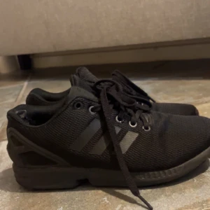 Svarta Adidas flux  - Svarta adidas flux, har inga defekter på utsidan endast lite avskrapat vid sulan där inne. Inget som synts. Sparsamt använda. Storlek 38,5