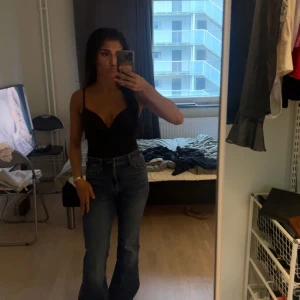 svart body hm - Snygg svart bodysuit med smala axelband och djup v-ringning. Perfekt för en stilren och enkel look.