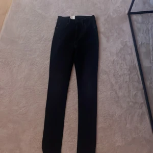 Svarta jeans från Tiger of Sweden - Snygga svarta jeans från Tiger of Sweden med en klassisk design. De har en hög midja och en slim passform som ger en stilren look. Perfekta för att matcha med olika outfits.