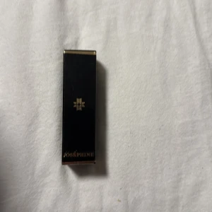 Läppstift från Joséphine - Elegant läppstift från Joséphine i nyansen 'Meet Philou'. Förpackningen är stilren och svart med guldiga detaljer. Perfekt för att ge en glamorös touch till din look.