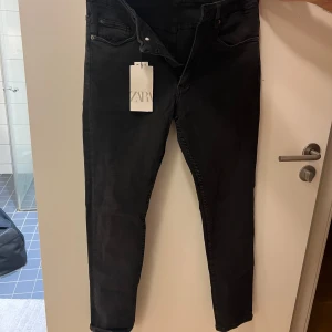 Svarta jeans från Zara - Snygga svarta jeans från Zara med en klassisk design. De har en dragkedja och knapp framtill samt fem fickor. Perfekta för en stilren look.