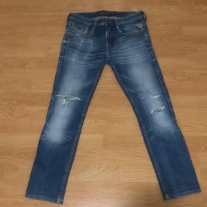 Blå reply jeans med slitningar - Snygga blå jeans med slitningar på framsidan och en klassisk femficksdesign. De har en knappgylf och en läderpatch på baksidan. Perfekta för en avslappnad stil.
