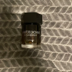 La Nuit De L'Homme L'Intense från Yves Saint Laurent - Säljer en flaska La Nuit De L'Homme L'Intense från Yves Saint Laurent. Flaskan har en elegant design med en mörk tonad glasflaska och en svart sexkantig kork. Parfymen kommer i en stilren svart och silverfärgad kartong.