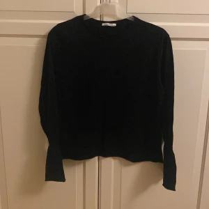 Svart trikåtröja från Zara - Säljer en stilren svart trikåtröja från Zara. Tröjan har långa ärmar med elastiska muddar och en rund halsringning. I fint skick. Storlek M.