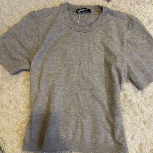 Grå kortärmad tröja från Gina Tricot - Säljer en stilren grå kortärmad tröja från Gina Tricot. Perfekt för en avslappnad look. Tröjan har en rund halsringning och är tillverkad i ett mjukt material.