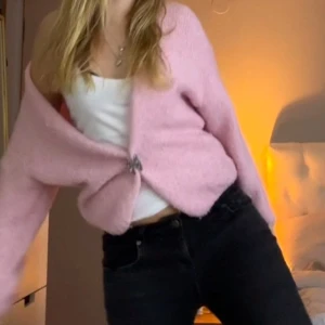 Rosa kofta med knäppning - Säljer en söt rosa. Koftan har en mjuk och fluffig textur och långa ärmar. Perfekt för att hålla sig varm och stilren under kyligare dagar.