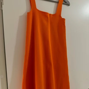 Orange klänning - Snygg och enkel orange klänning med ärmlös design. Perfekt för en färgglad look. Klänningen har en rak passform och är gjord i ett mjukt material som ger en bekväm känsla.