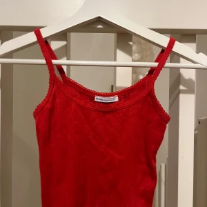 Röd linnetopp från Bershka - Snygg röd linnetopp från Bershka med smala axelband. Perfekt för varma dagar eller som ett lager under en jacka. Enkel och stilren design som passar till det mesta.