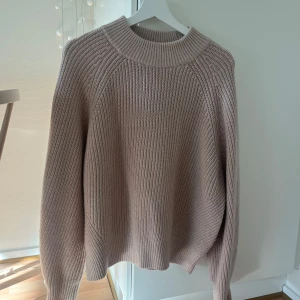 Beige stickad tröja - Aldrig använd! Lite oversize i storleken. Mysig beige stickad tröja med rund hals och långa ärmar. Perfekt för kyliga dagar med sin ribbade struktur som ger en stilren look. Passar bra till både jeans och kjol.