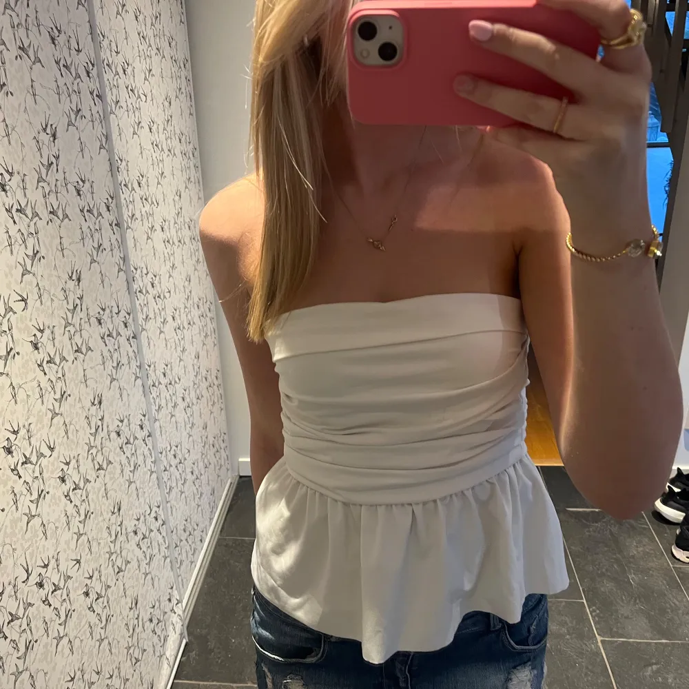 Säljer min fina vita axelbandslösa topp med rynkade detaljer och volang nedtill. Så snygg och i toppskick!!🤍☺️. Yläosat.