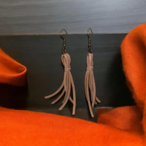 Beige fransiga örhängen - Snygga beige örhängen med fransar som ger en bohemisk touch. Perfekta för att lägga till lite stil och rörelse till din outfit. De är lätta och bekväma att bära hela dagen.