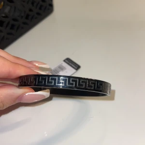 Svart armband i rostfritt stål - Köpte när jag var utomlands, går att diskutera pris. Snyggt svart armband i rostfritt stål med ett geometriskt mönster. Perfekt för att ge en stilren touch till din outfit.