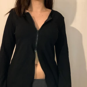 Svart tröja med dragkedja - Snygg svart tröja med dragkedja framtill. Perfekt för en casual look och kan enkelt matchas med olika outfits. Tröjan har långa ärmar och en stilren design.